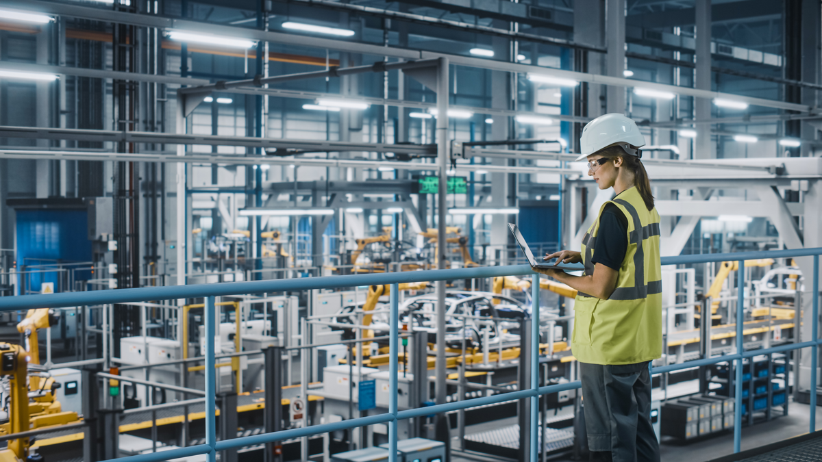 Woman in yellow safety best in front of manufacturing belt