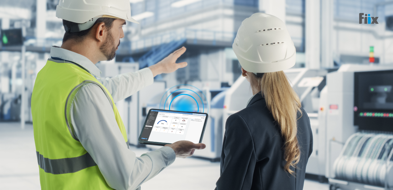 Two maintenance managers on a facility floor with the Fiix CMMS being used on their tablet